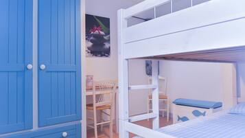 Une chambre d’enfant avec des lits superposés, un bureau et une chaise.