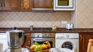 A kitchen with wooden cabinets, a microwave, a toaster, and a washing machine. - Apartment 'La Viña 2' with Mountain Views and Wi-Fi (Corao)