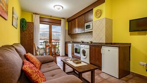 A living room with a sofa, a table, and a kitchen area with appliances. - Apartment 'La Viña 2' with Mountain Views and Wi-Fi (Corao)