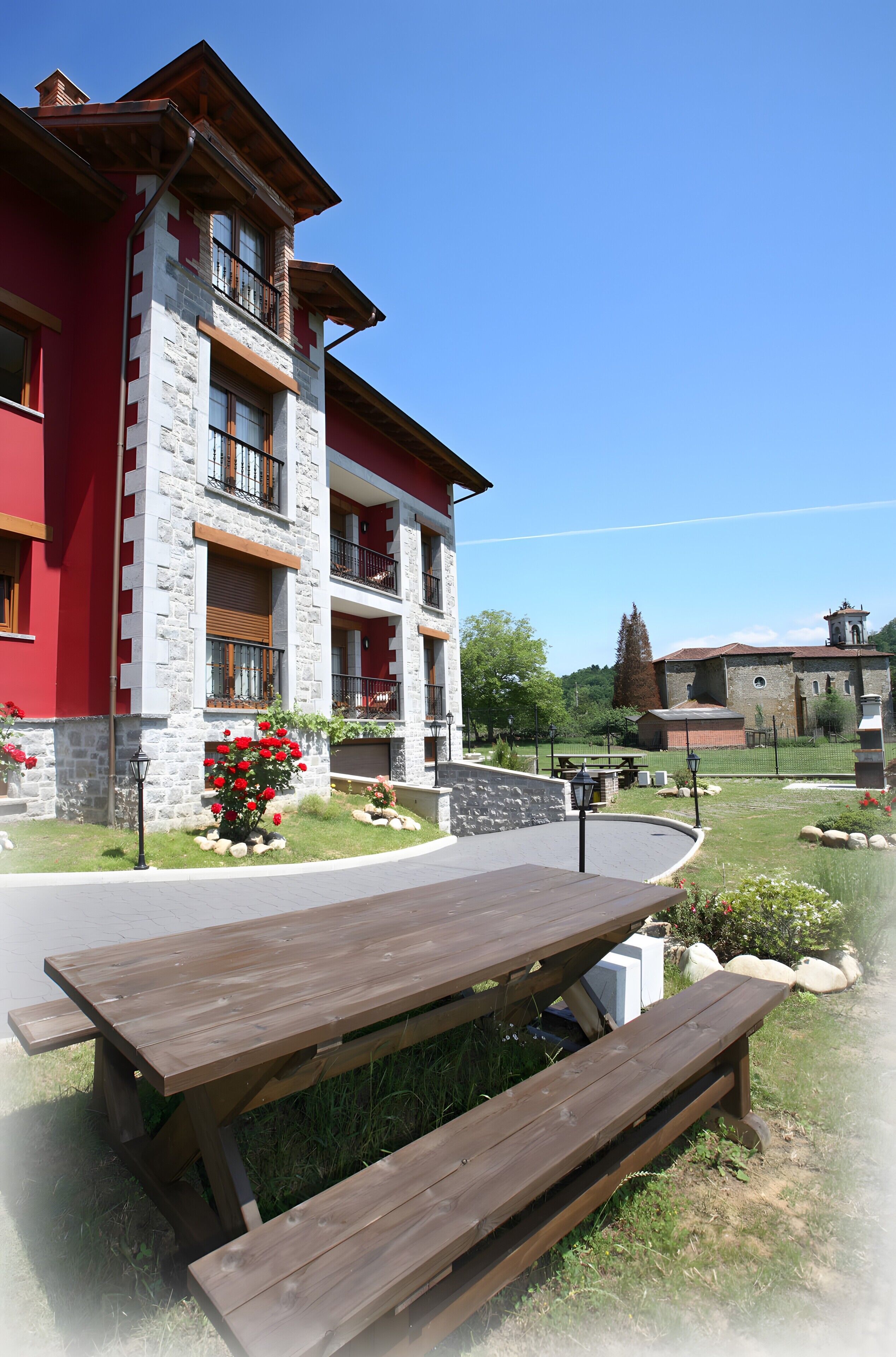 A multi-story building with a stone facade, balconies, and a picnic table in the foreground.