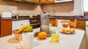 A kitchen with wooden cabinets, a coffee maker, a basket of fruit, a plate of croissants, and a glass of orange juice. - Apartment 'La Viña 3' with Mountain Views and Wi-Fi (Corao)