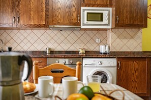 A kitchen with wooden cabinets, a microwave, a washing machine, and a coffee maker. - Apartment 'La Viña 6' with Mountain Views and Wi-Fi (Corao)