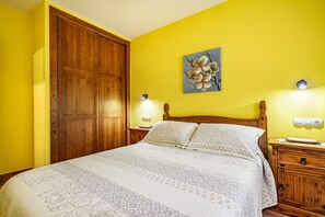 Une chambre à coucher avec un lit, une armoire en bois, des lampes de chevet et un tableau mural.