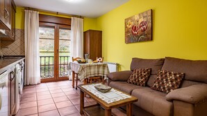 A kitchen with a dining area, a sofa, and a table with a basket. - Apartment 'La Viña 7' – Perfect for Couples' Getaways (Corao)