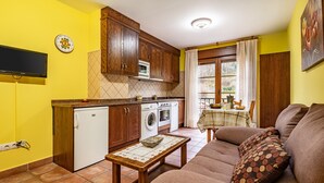 A compact kitchen with wooden cabinets, a built-in microwave, and a dining area with a table and chairs. - Apartment 'La Viña 7' – Perfect for Couples' Getaways (Corao)