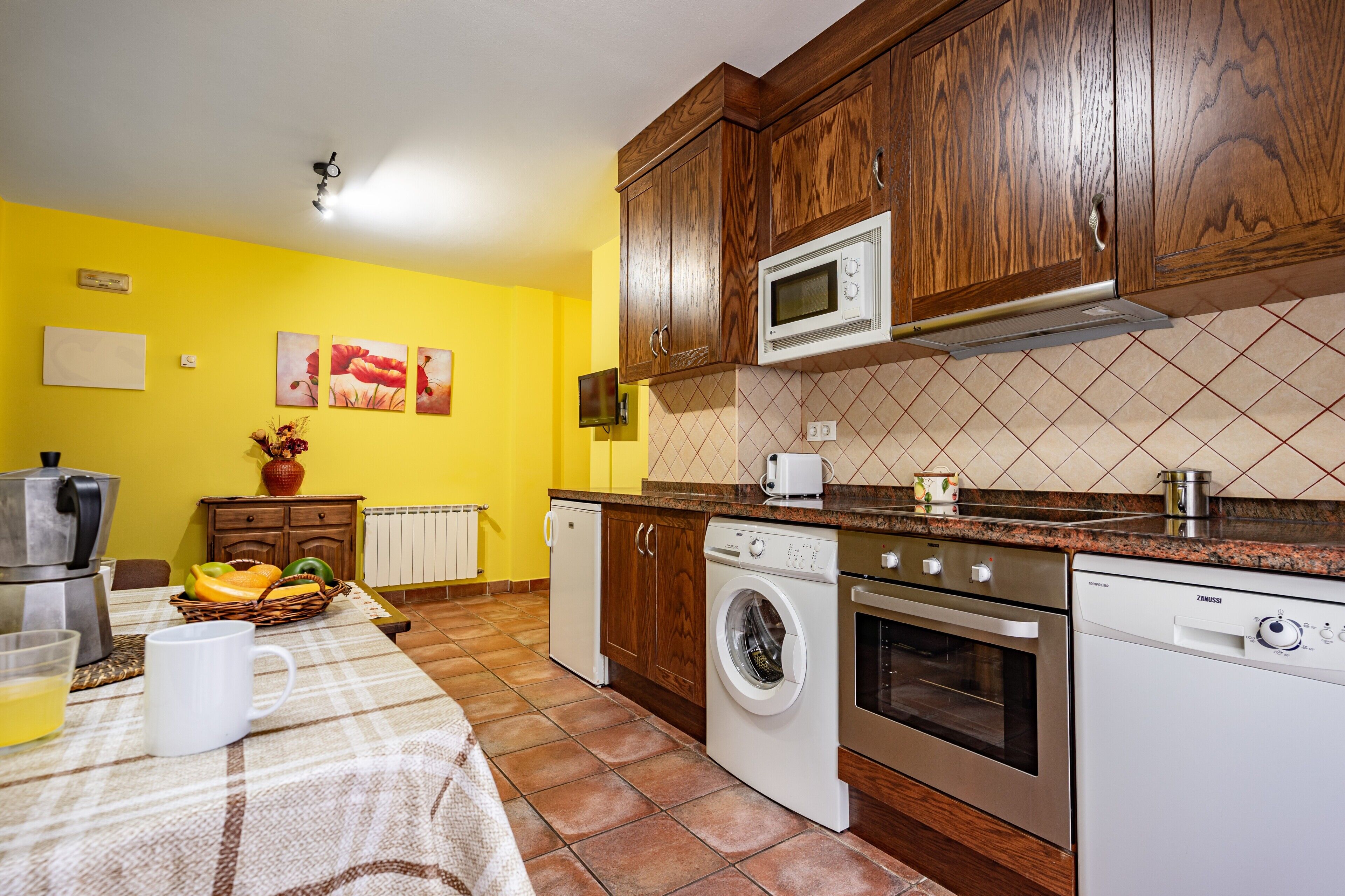 A kitchen with wooden cabinets, a microwave, a washing machine, and a coffee maker.