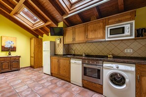 A kitchen with wooden cabinets, a microwave, a dishwasher, and a washing machine. - Apartment 'La Viña 8' with Wi-Fi (Corao)