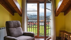 A room with a view of a green landscape, a brown chair, and a wooden table. - Apartment 'La Viña 9' with Mountain Views and Wi-Fi (Corao)