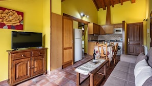 A living room with a television, wooden cabinets, a sofa, and a dining area with a table and chairs. - Apartment 'La Viña 9' with Mountain Views and Wi-Fi (Corao)