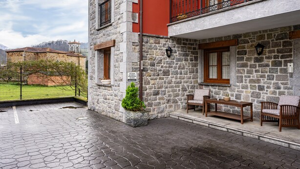 A stone building with a balcony, a small garden, and a paved patio area. - Apartment 'La Viña 9' with Mountain Views and Wi-Fi (Corao)