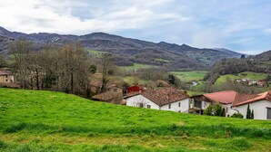 A rural landscape with rolling hills, a white building with a red roof, and a clear sky. - Apartment 'La Viña 9' with Mountain Views and Wi-Fi (Corao)