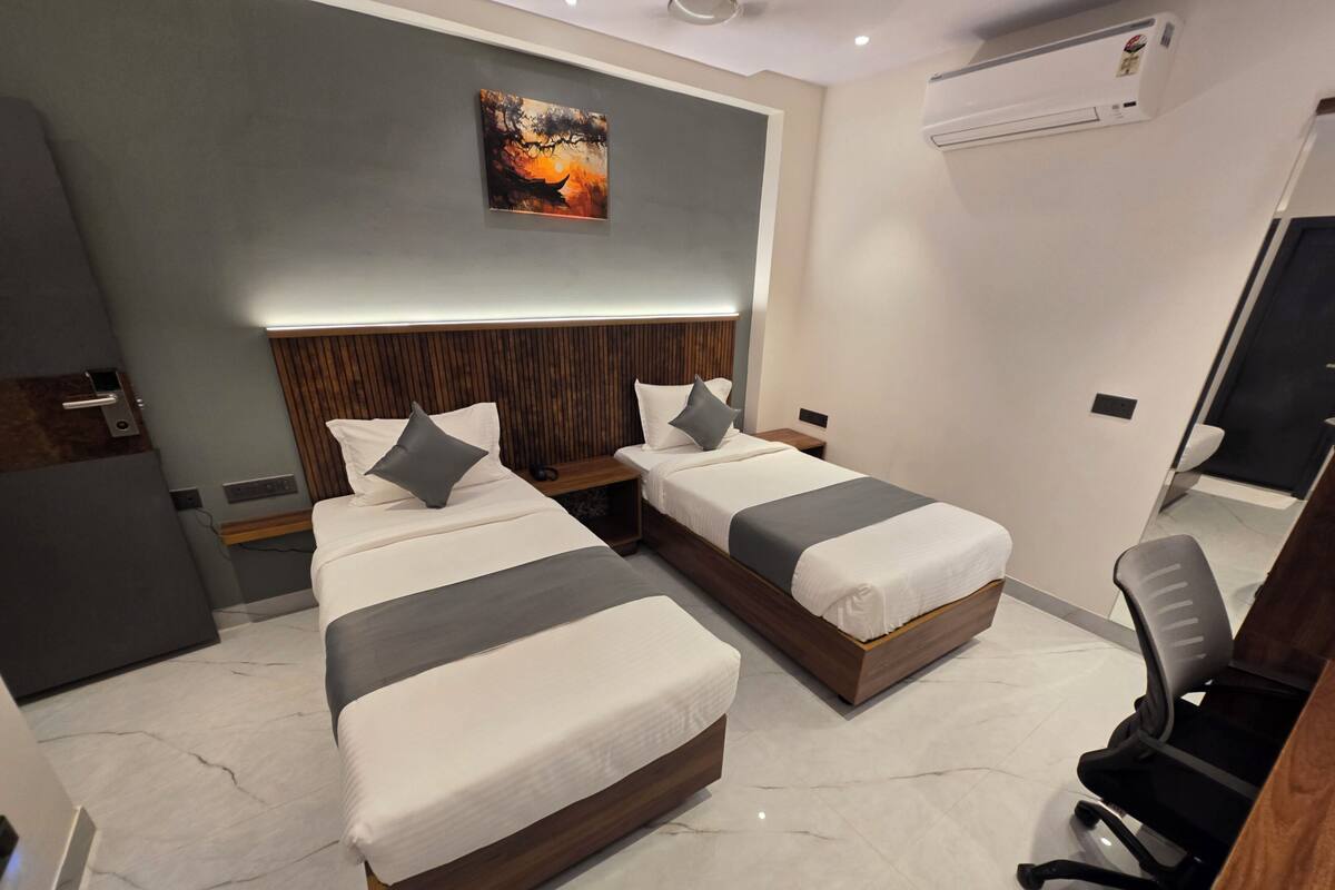 A modern hotel room with two beds, a wooden headboard, a painting on the wall, and a desk with a chair.