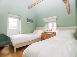A bedroom with two single beds, a dresser, a window with a view, and a painting on the wall.