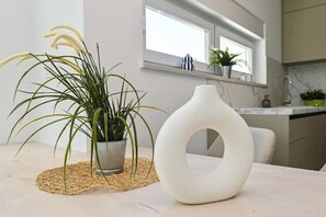 Eine moderne Küche mit einem Blumentopf und einer weißen Vase auf einem Tisch.