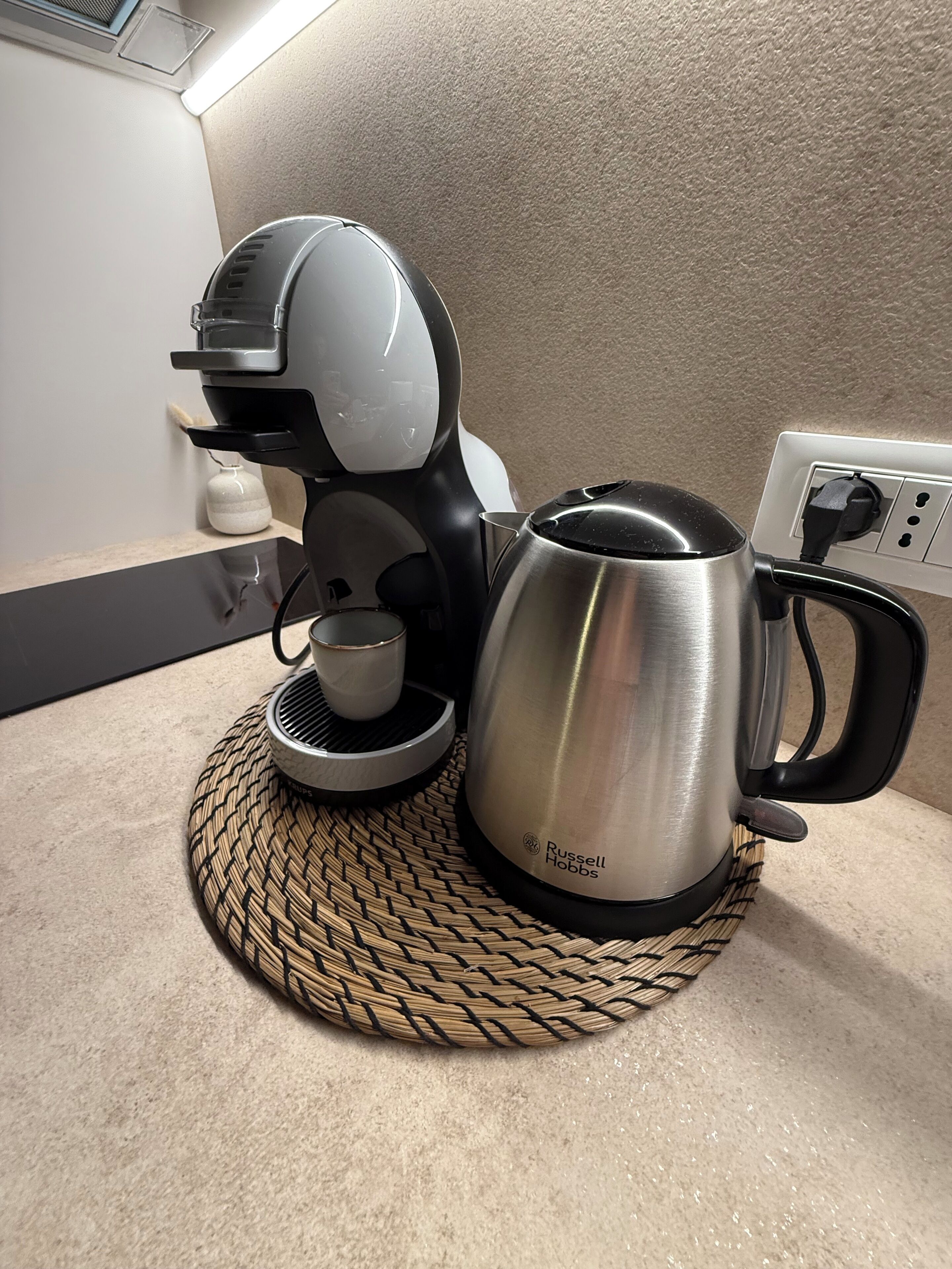 Una cafetera y un hervidor sobre una estera tejida.