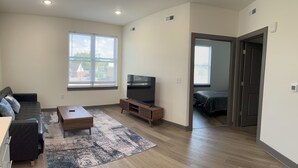 Una sala de estar moderna con sofá, mesa de centro, televisor y vistas por una ventana.