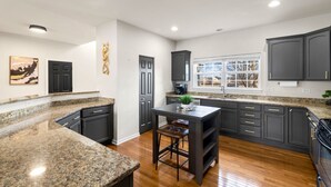 A spacious kitchen with granite countertops, dark cabinetry, and a large window providing natural light. - Luxury 4 Bedroom Home Elgin (Elgin)