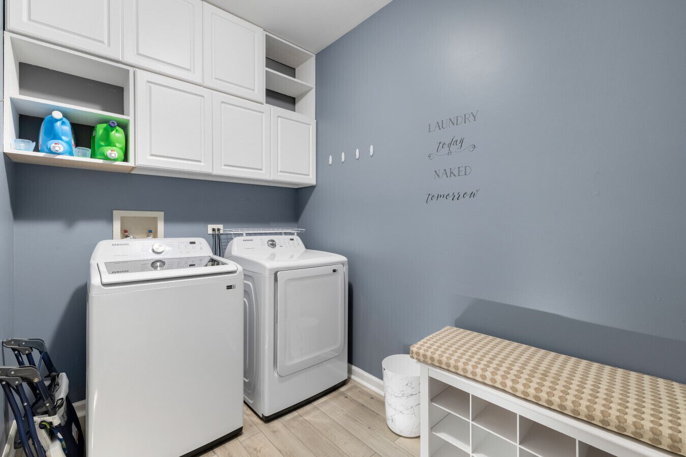 A laundry room with a washing machine, dryer, and shelves with detergent bottles.