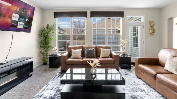 A modern living room with a leather sofa, a coffee table, and a flat-screen TV displaying streaming services. - Luxury 4 Bedroom Home Elgin (Elgin)