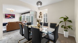 A modern dining area with a glass table, black chairs, and a central vase. - Luxury 4 Bedroom Home Elgin (Elgin)