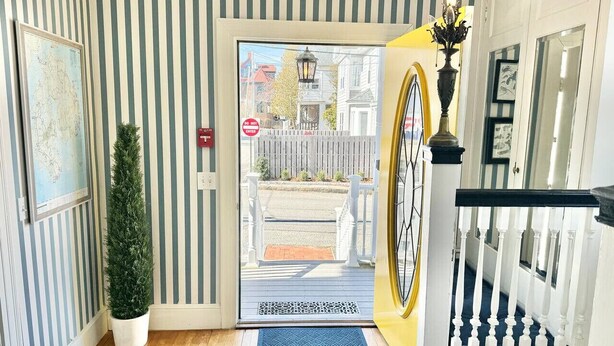 A hotel entrance with striped walls, a potted plant, a do not enter sign, a yellow door, and a black and white railing. - The Cottage Room at Lafayette Inn (Bar Harbor)