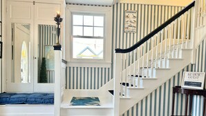 A staircase with white railings and a striped wall. - The Cottage Room at Lafayette Inn (Bar Harbor)