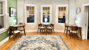 A dining room with a ceiling fan, two dining tables with chairs, and a large rug. - The Cottage Room at Lafayette Inn (Bar Harbor)
