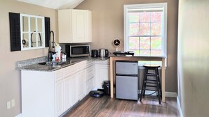 A kitchen with white cabinets, a microwave, a coffee maker, and a refrigerator. - Charming Guesthouse (Middleton)
