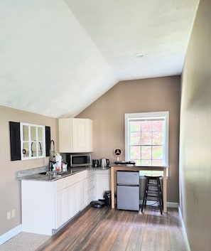 A kitchen with white cabinets, a microwave, a coffee maker, and a refrigerator.