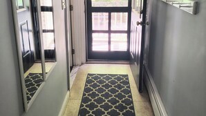 A hallway with a black and white patterned rug, a door leading outside, and a wall-mounted coat rack. - Charming Guesthouse (Middleton)