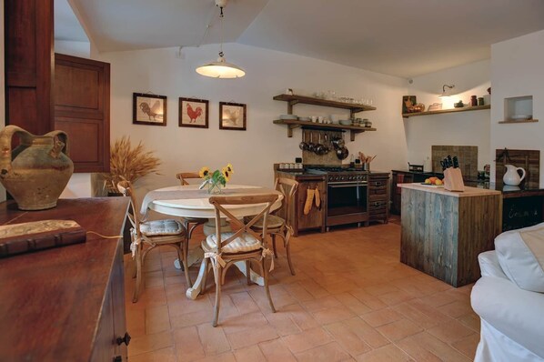 Una cocina acogedora con una mesa redonda, sillas de madera y una isla central con un lavamanos.