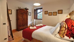 Un dormitorio con cama, un armario de madera, un radiador y cuadros en la pared.