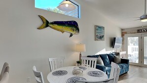 Un comedor con una mesa redonda blanca, sillas blancas y una decoración de pez en la pared.