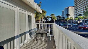 Un balcón con vista a una calle de la ciudad, palmeras y un edificio alto.
