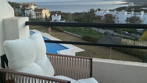 A balcony with a view of a coastal landscape, including buildings and a body of water. - Casa María Luisa: Panoramic Terrace, Spectacular Gibraltar Views & Separate Studio (Manilva)