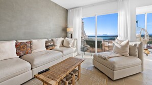 A modern living room with a sofa, a coffee table, and a view of the ocean. - Casa María Luisa: Panoramic Terrace, Spectacular Gibraltar Views & Separate Studio (Manilva)