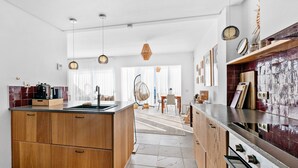 A modern kitchen with wooden cabinets, a central island, and a stove. - Casa María Luisa: Panoramic Terrace, Spectacular Gibraltar Views & Separate Studio (Manilva)