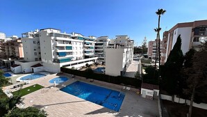 Un edificio residencial con varios balcones, piscina y un pequeño jardín.