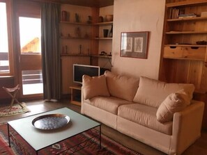 A living room with a beige sofa, a glass coffee table, and a television on a stand. - Ideal stay in the heart of the ski slopes (Val-d'Isère)