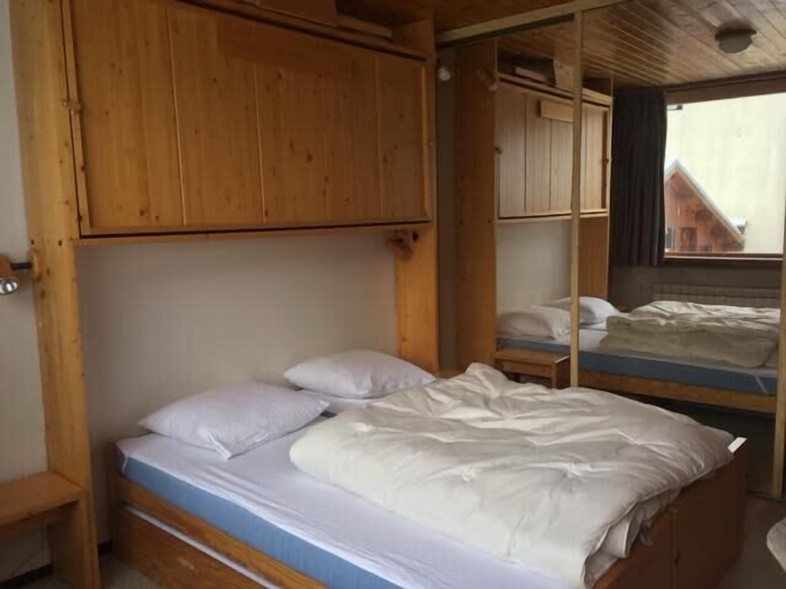 A wooden bunk bed room with a window and a door.