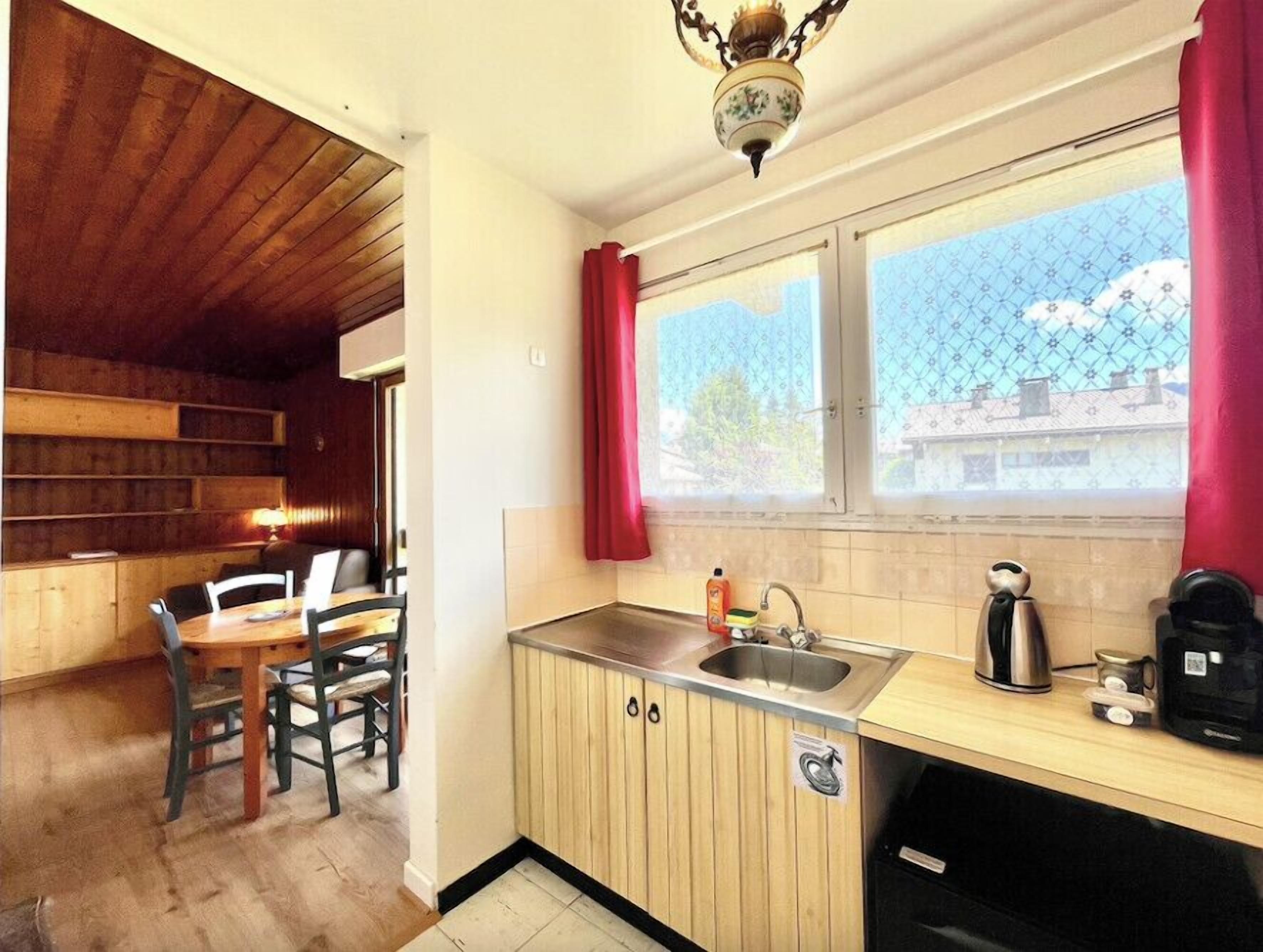 A compact kitchen with wooden cabinets, a sink, and a window with a view of buildings.