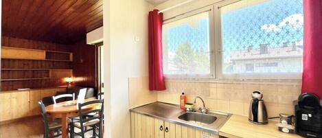 A compact kitchen with wooden cabinets, a sink, and a window with a view of buildings.