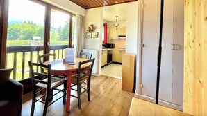 A cozy room with a wooden ceiling, a dining table with chairs, a large window, and a view of greenery outside. - Superb apartment in Megève (Megève)