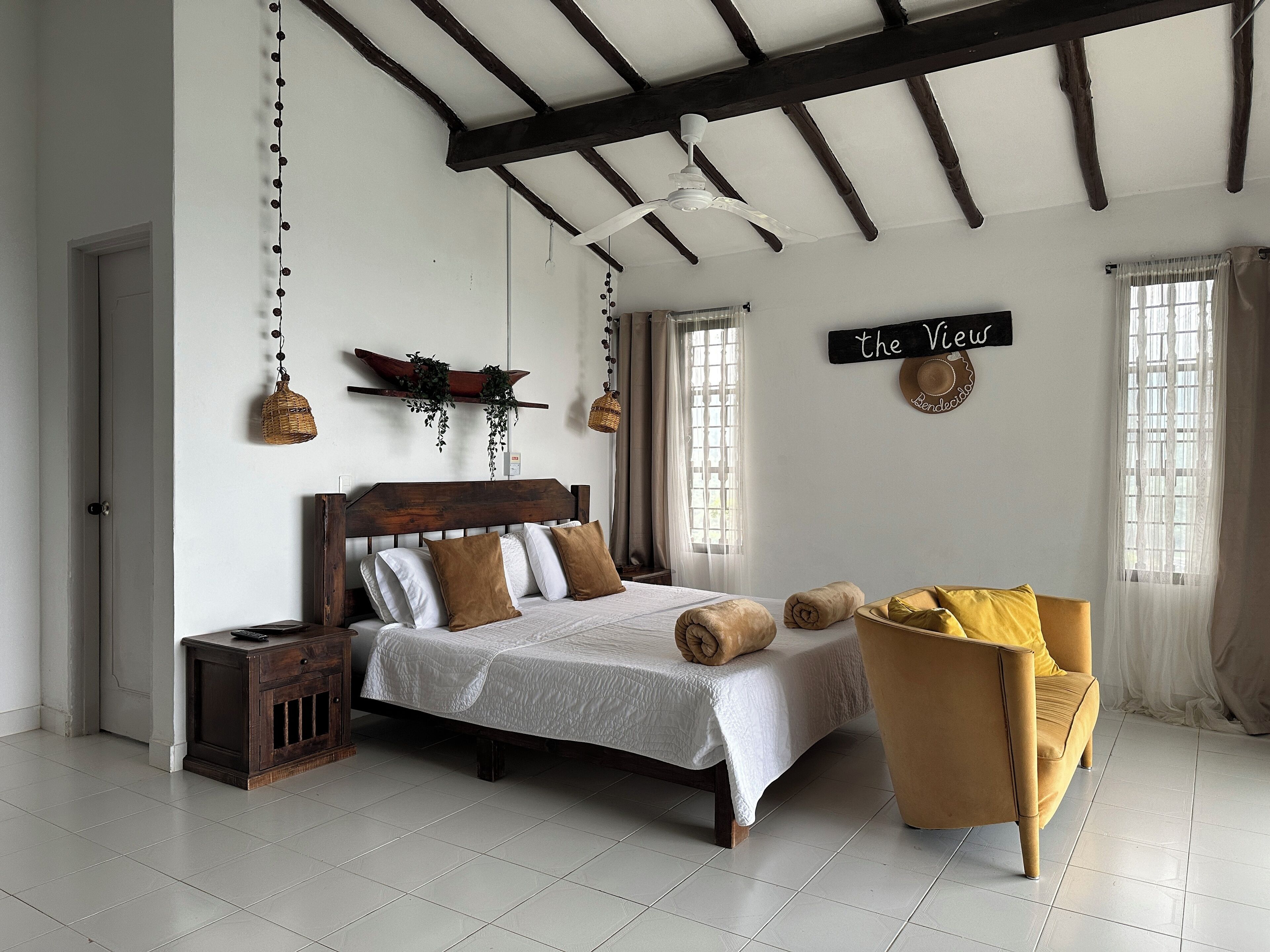A bedroom with a wooden bed, a small bedside table, a chair, and a ceiling fan.