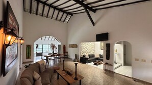 A spacious living area with a high ceiling, a dining area with a table and chairs, a sofa, and a stone accent wall. - La Villa The View (Cali)