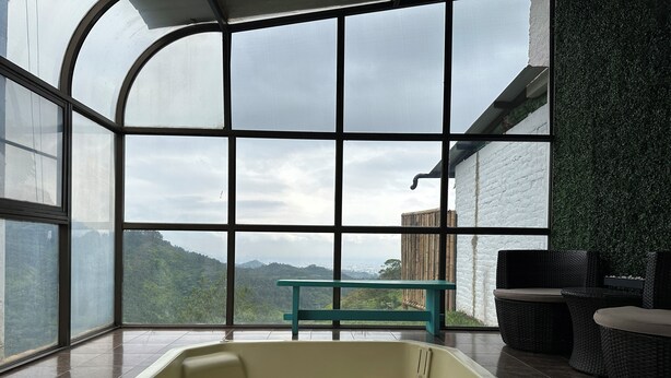 A spa area with a large window, a hot tub, and wicker furniture. - La Villa The View (Cali)