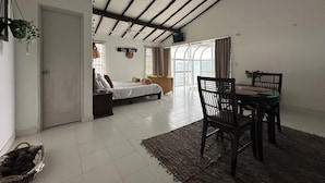 A spacious room with a bed, a dining table with chairs, a large window with curtains, and a ceiling fan. - La Villa The View (Cali)