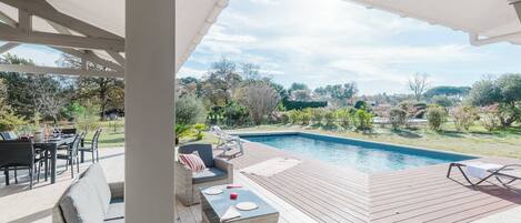 Una terrazza esterna con piscina, mobili in vimini e vista sul paesaggio circostante.