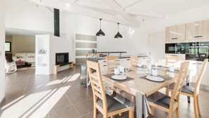 A modern kitchen with white cabinets, a built-in oven, and a dining area with a wooden table and chairs.