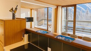 Una cocina moderna con armarios de madera, estufa integrada y ventana con vista a una montaña nevada.